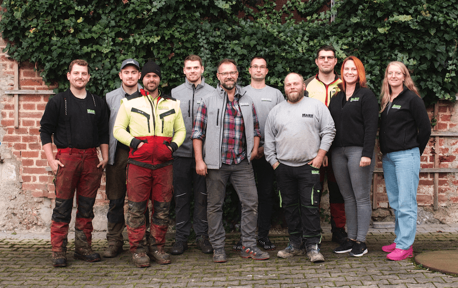 10 Mitarbeiter vor einer Steinmauer